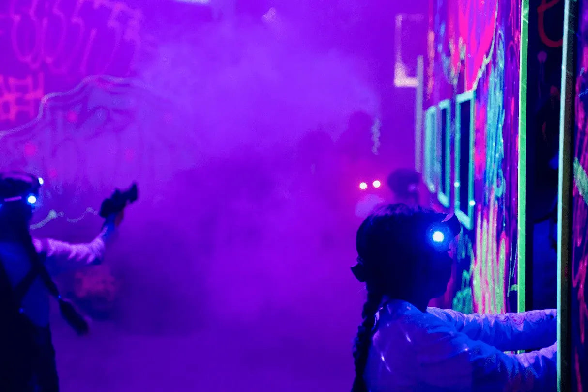 Two girls in the laser tag area with smoke and neon lights