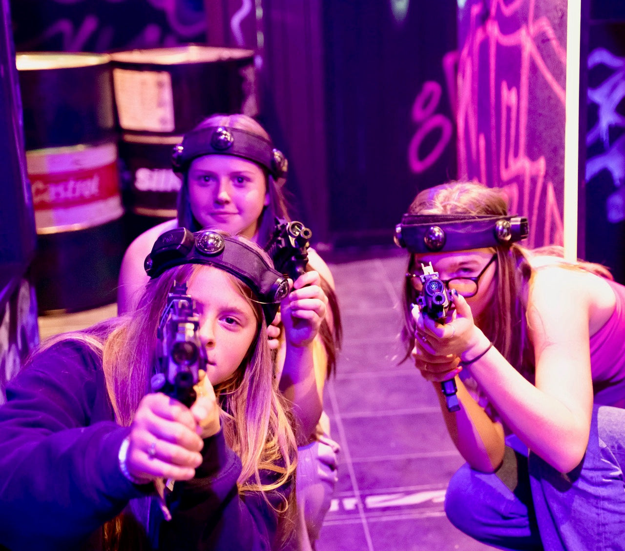 Three girls aiming towards the camera with laser tag guns